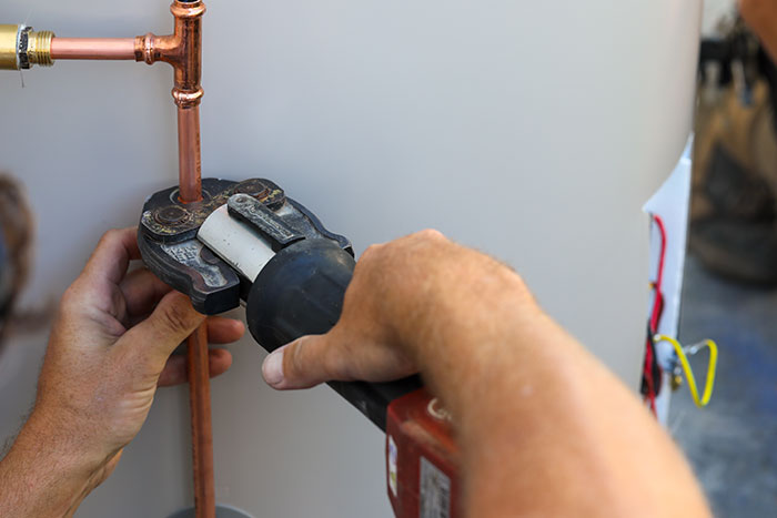 Plumber crimping copper pipes on a hot water system in Bribie Island